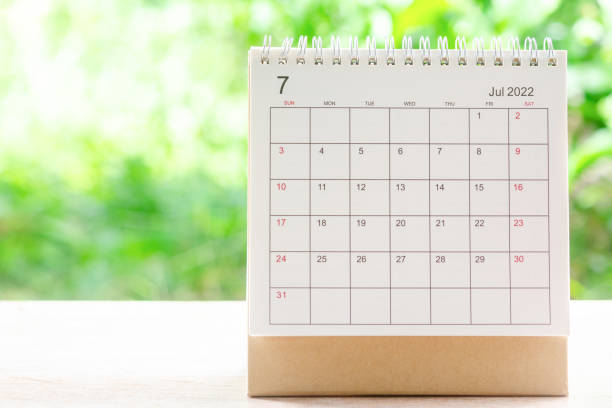 July month, Calendar desk 2022 for organizer to planning and reminder on wooden table with green nature background. stock photo
