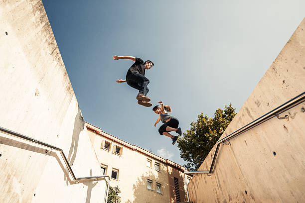 Jumping and practicing parkour in the city Urban parkour Young woman and man jumping aluxum stock pictures, royalty-free photos & images