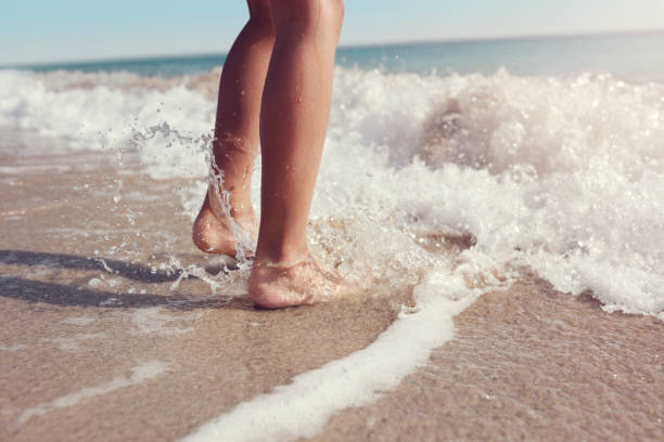 jumping in the sea waves on the beach - voeten in het zand stockfoto's en -beelden