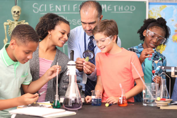 Junior high age school students conduct science experiments in classroom. Junior high, high school age students work on science experiments in school classroom setting.  STEM topics.  Laboratory glassware, microscope. middle school teacher stock pictures, royalty-free photos & images