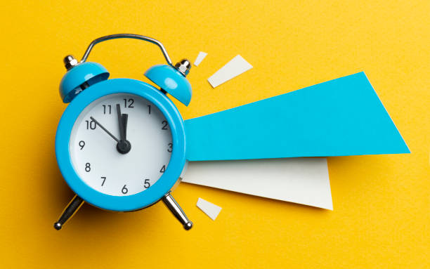 Just in Time Alarm clock and colour papers on the yellow background. clock photos stock pictures, royalty-free photos & images