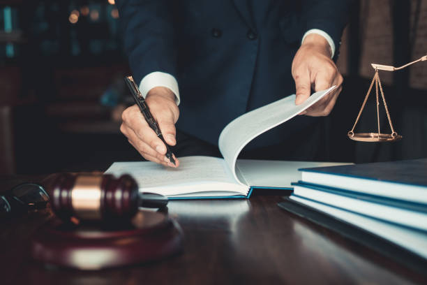Justice and law concept. Gavel on sounding block in hand's Male judge at a courtroom, working with document law books, report the case on table in modern office. stock photo