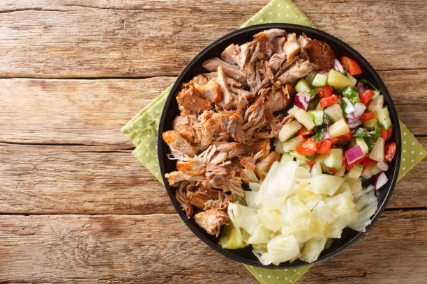 Kalua pork hawaiian food slowly cooked and served with stewed cabbage and fresh salad close-up in a plate. horizontall top view stock photo