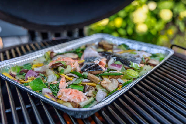 Kamado barbecue mixed vegetables and salmon on 
aluminium griddle plate stock photo