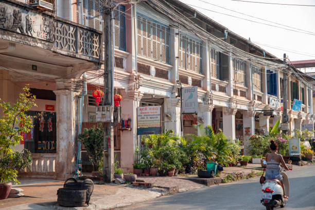 Kampot, Cambodia - 12 April 2018: town view with french colonial buildings and khmer woman on scooter. stock photo