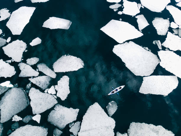 Kayak sailing between ice floes on the lake stock photo