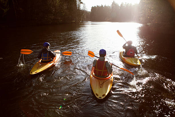 kayakers rowing together on still lake - kajak stockfoto's en -beelden