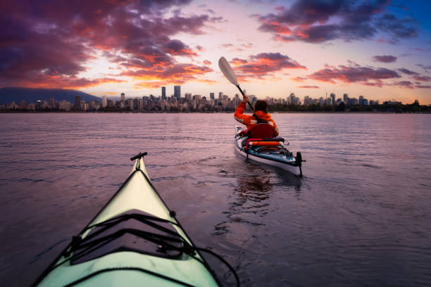 Kayaking in the ocean with modern city and mountains in background. stock photo