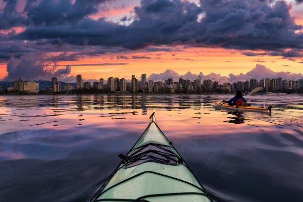 Kayaking in the ocean with modern city and mountains stock photo