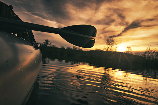 kayaking on a lake in the sunset with closeup on the paddle