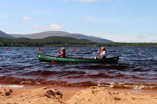 Adult and child kayaking on Loch Morlich in Aviemore, Scotland on a sunny day during August 2021 summer vacation