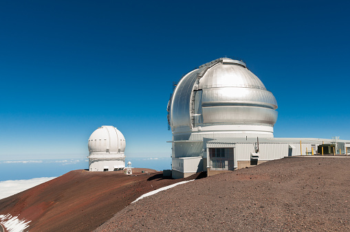 Gemini North Observatory on top of Mauna Kea mountain peak on Big Island of Hawaii, United States with deep blue sky and volcanic landscape.