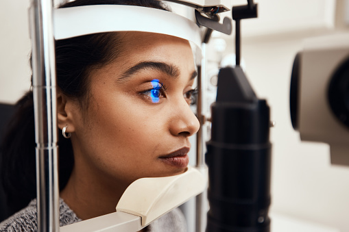 Shot of a young woman getting her eye’s examined with a slit lamp