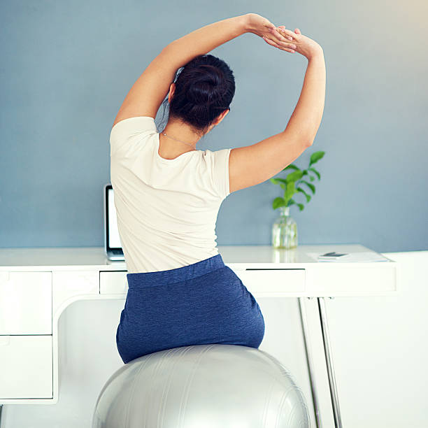 Keep the blood flowing Rearview shot of a young businesswoman stretching while working at homehttp://195.154.178.81/DATA/i_collage/pi/shoots/806156.jpg yoga ball work stock pictures, royalty-free photos & images