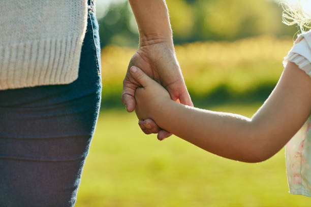 Keep them close, keep them safe Cropped shot of a little girl holding an unrecognizable woman’s hand in the park holding hands stock pictures, royalty-free photos & images