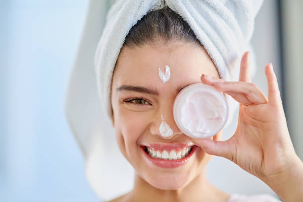 Keep your skin healthy Cropped portrait of a beautiful young woman applying moisturizer to her skin in the bathroom at home skin cream stock pictures, royalty-free photos & images