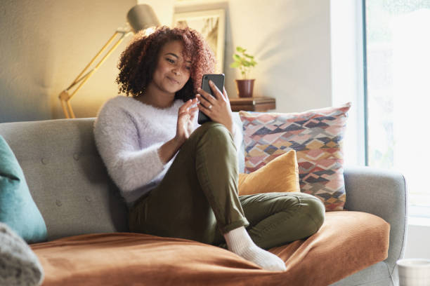 Keeping her social life alive while stuck at home Shot of a young woman using a cellphone while relaxing at home free images for downloads stock pictures, royalty-free photos & images