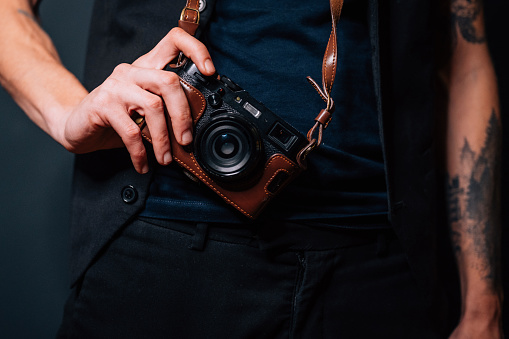 A young man in a blue shirt and an old camera hanged on his neck ready to shoot. Photography concept