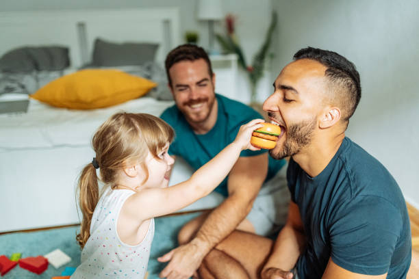 Keeping mental health in LGBT families with kids during lockdown and pandemic Gay couple playing with their adopted daughter girl and enjoying the parenthood gay person stock pictures, royalty-free photos & images