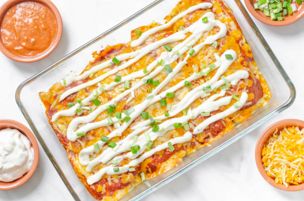 Keto ground beef enchiladas casserole Mexican food, homemade beef ground enchiladas in a ketogenic style with cheese tortillas in a glass oven dish on a white background with ingredients - directly above view casserole dish stock pictures, royalty-free photos & images