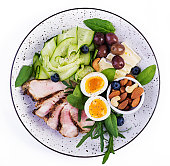 Ketogenic diet. Keto brunch. Boiled egg, pork steak and olives, cucumber, spinach, brie cheese, nuts and blueberry. Top view