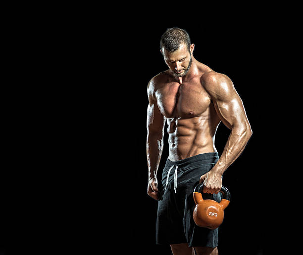 Kettlebell in hands Handsome bodybuilder standing with kettlebell in hands. Isolated. male bodybuilders stock pictures, royalty-free photos & images