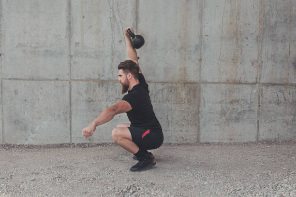 Kettlebell overhead squats performed by young male athlete stock photo