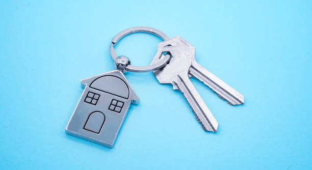 파란색 배경에 집 기호와 키가 있는 키 체인, 부동산 개념 - home 뉴스 사진 이미지