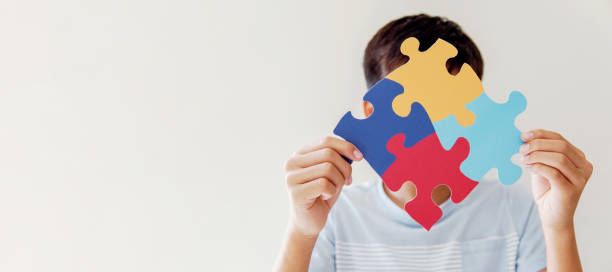 Kid boy hands holding puzzle jigsaw,  mental health concept, world autism awareness day stock photo