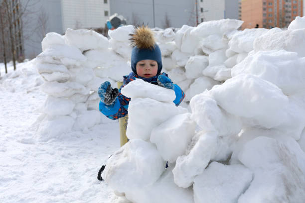 Kid building snow fortress Kid building snow fortress at winter playground fort stock pictures, royalty-free photos & images