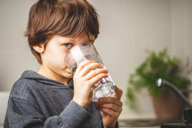 Kid drinking clean tap water at home stock photo