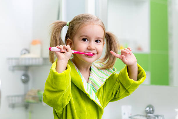 kid girl brushing teeth in bathroom stock photo