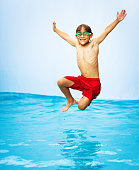 eighth years old kid jumping in a pool just about to hit the water
