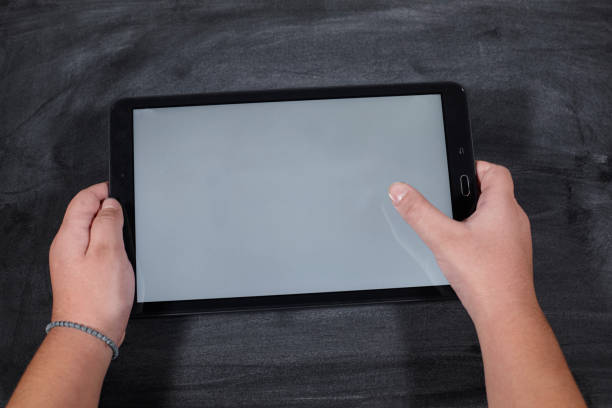 kid holding a tablet on wooden table. e-learning school. stock photo