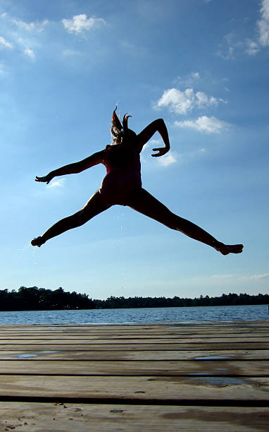 Kid jumps into lake off dock stock photo