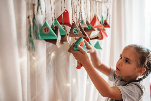 Kid opening handmade advent calendar with color paper triangles. Seasonal activity for kids stock photo