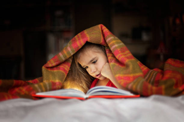 Kid reading a book on bed stock photo