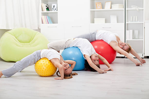 Kids and woman doing stretching exercises - using large balls