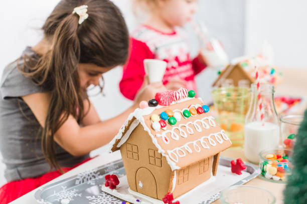 Kids decorating small gingerbread houses at the Christmas craft party stock photo