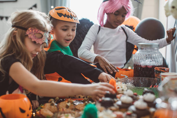 Kids eating on Halloween party Multi ethnic group of children have party at home, they wear costumes, celebrating Halloween and enjoy in spooky food stage costume stock pictures, royalty-free photos & images