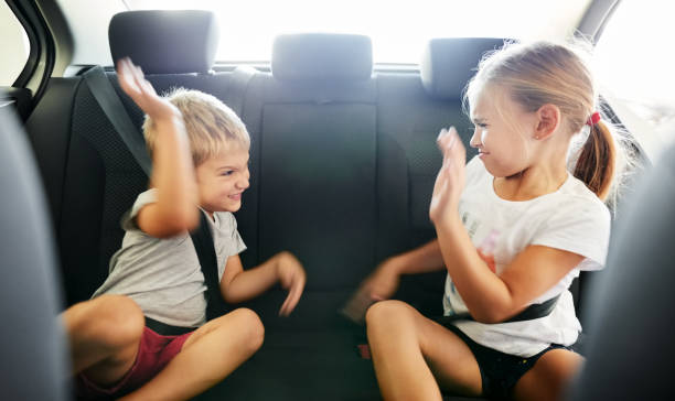 Kids fighting in the car Shot of small brother and sister sitting in car backseat and fighting while traveling back seat stock pictures, royalty-free photos & images