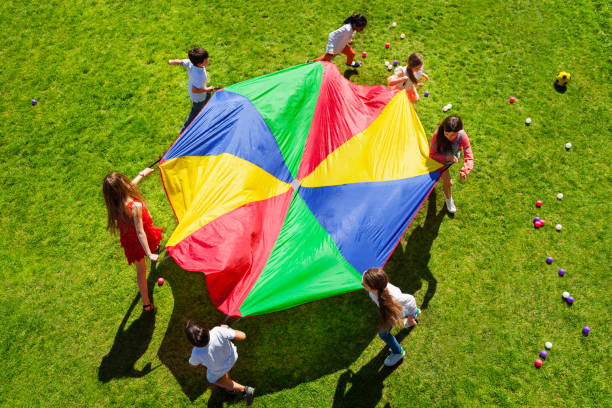 Kids going round in a circle with bright parachute stock photo