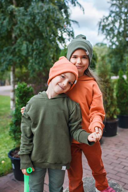 Kids in trendy hats and hoodies having fun in park, fall vibes, autumn beauty style, child fashion stock photo