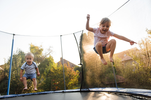 Siblings having fun together outside on trampoline