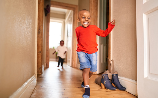 Boy running in hallway with his sister chasing him at home