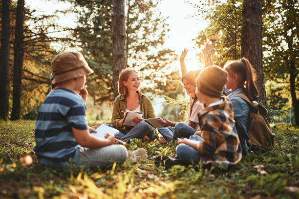 Kids raising hands asking questions during outdoor lesson with t stock photo