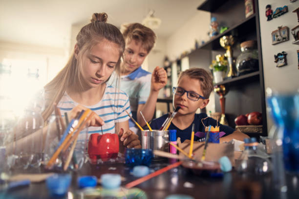 Kids upcycling - creating new fun stuff from used stuff Three kids making fun stuff from garbage at home. They are using plastic bottles, cans to create toys and useful stuff. The girl is gluing a stem to an apple made of painted plastic bottle bottoms.
Nikon D850 upcycling stock pictures, royalty-free photos & images
