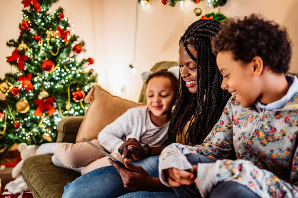 Kids watching cartoons with mom on tablet Kids watching cartoons with mom on tablet or having video call. Christmas time. christmas story telling stock pictures, royalty-free photos & images