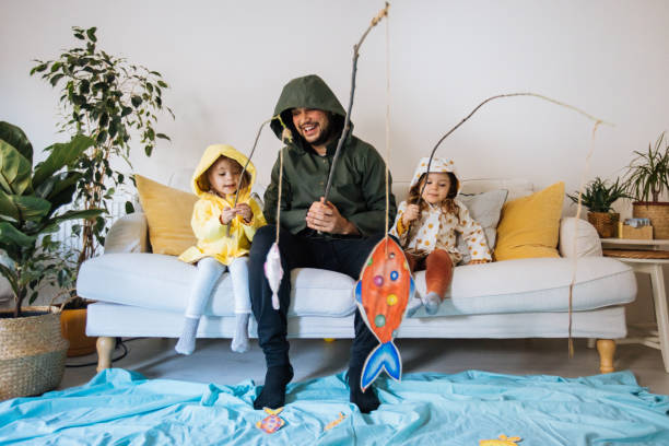 Kids with father playing fishing at home Happy child and young father with inflatable ring and drawing tropical fishes around him sofa photos stock pictures, royalty-free photos & images