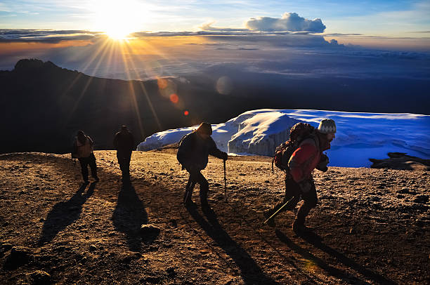 Kilimanjaro Climbers "The rising sun breaks through the clouds as climbers near the summit of Mt. Kilimanjaro, Tanzania." mt kilimanjaro photos stock pictures, royalty-free photos & images